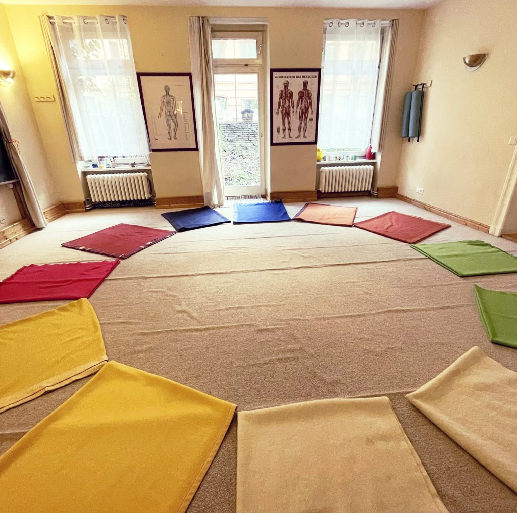 Shiatsu Raum mit bunten Decken, die im Kreis auf dem Boden liegen - als Anordnung der Organuhr.